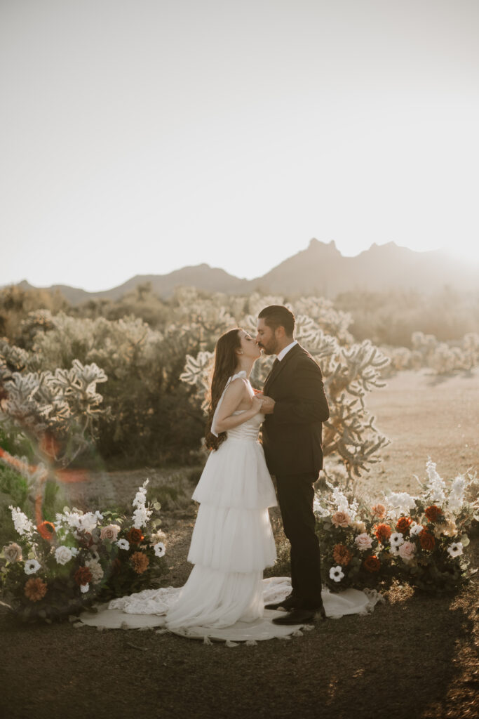 Black and white photo of a bride and groom in the Arizona desert wearing a wedding dress and black suite.