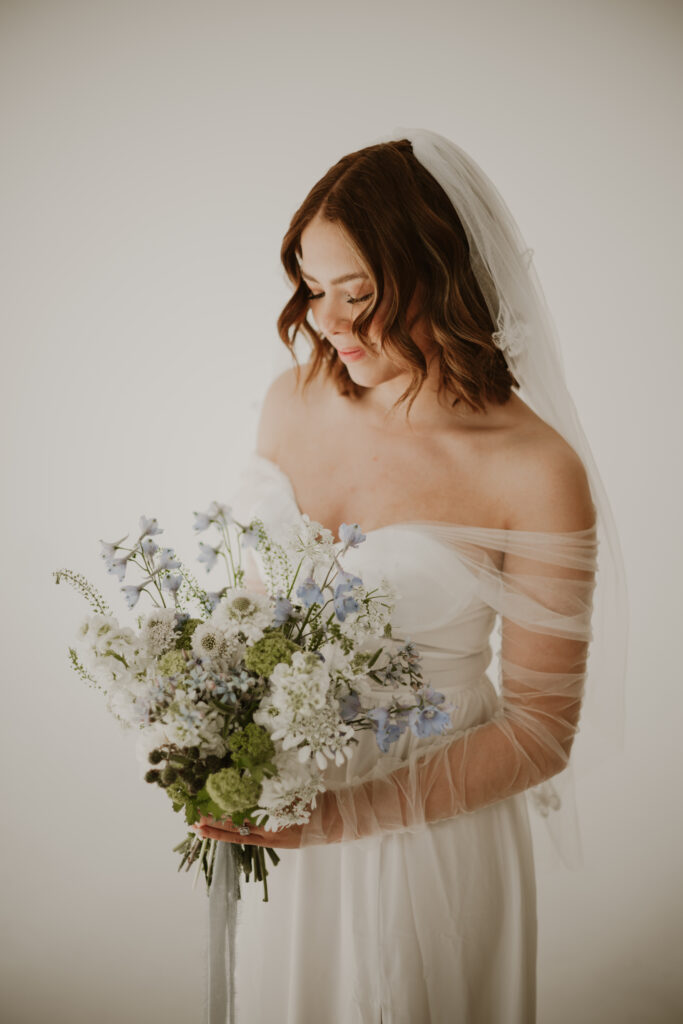 A bridal styled shoot in a studio with a blue and white bouquet. 