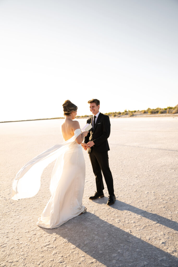 Untraditional wedding at the Utah salt flats with a bride in a wedding dress and groom in a black suit.