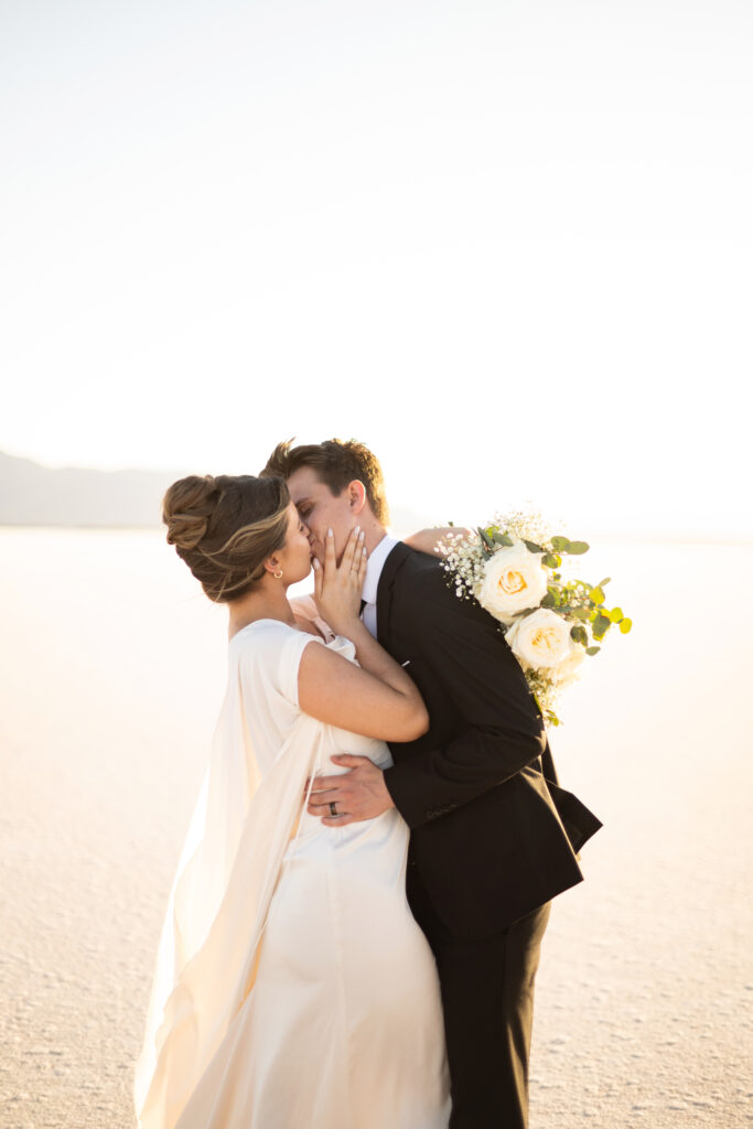 Untraditional wedding at the Utah salt flats with a bride in a wedding dress and groom in a black suit.