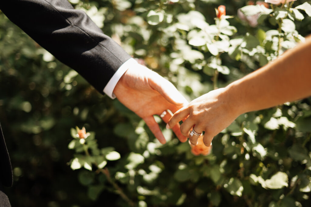 Bride and groom holding hands in a garden after their wedding ceremony
