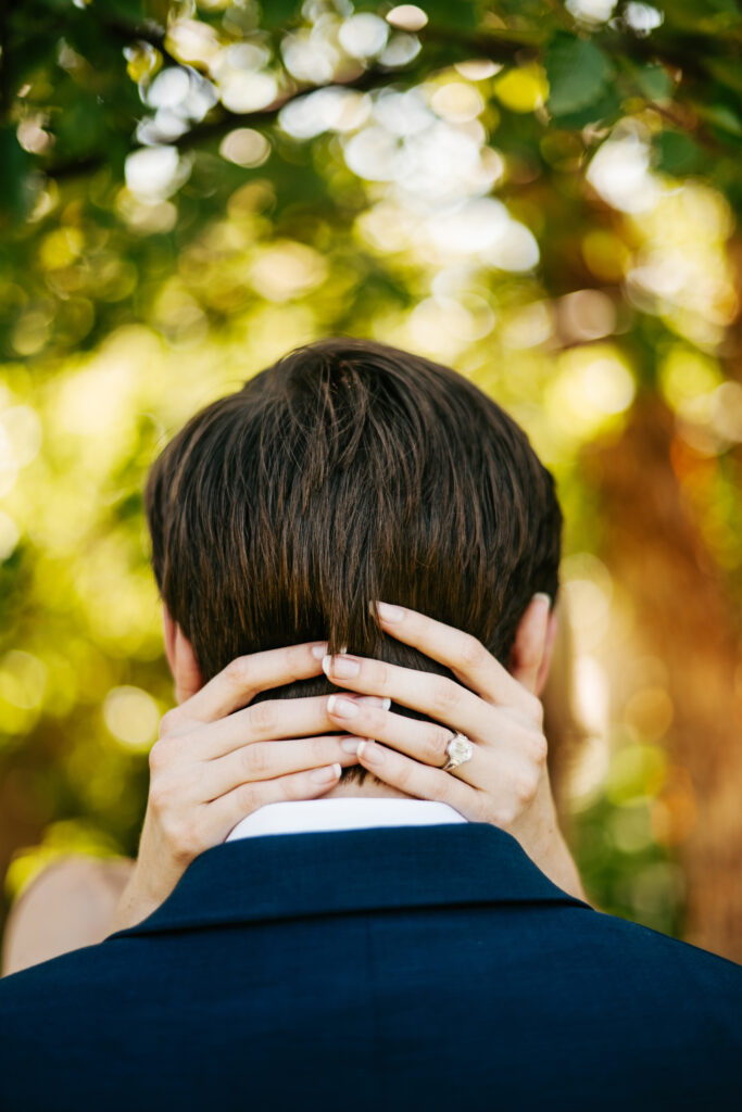 Engagement photos of ring on the girl's hand with her wands wrapped around the back of the guy's neck. 