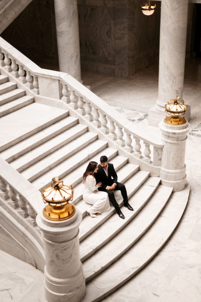 Engaged couple sitting on the stairs in the Utah state capitol building in Salt Lake City.