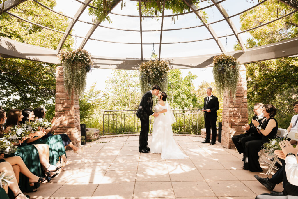 Bride and groom kissing during their ceremony at an outdoor garden wedding venue in northern Utah
