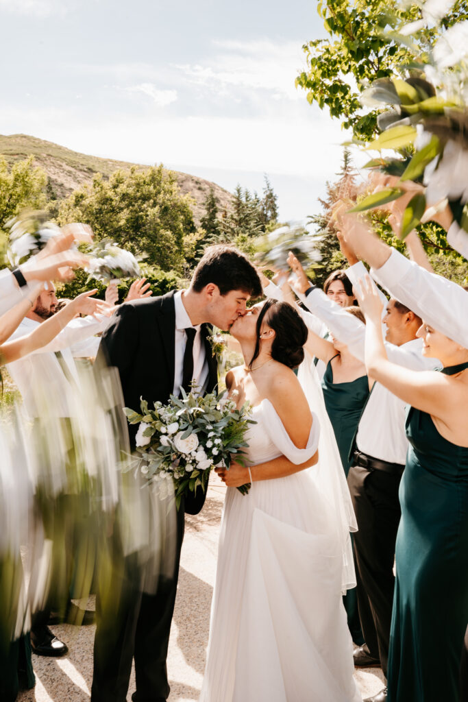 bride and groom kissing with people blurry around them