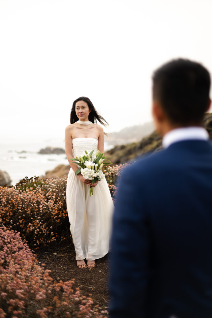 Bride and groom eloping on a cliff side in Big Sur California mid day during wild flower season.