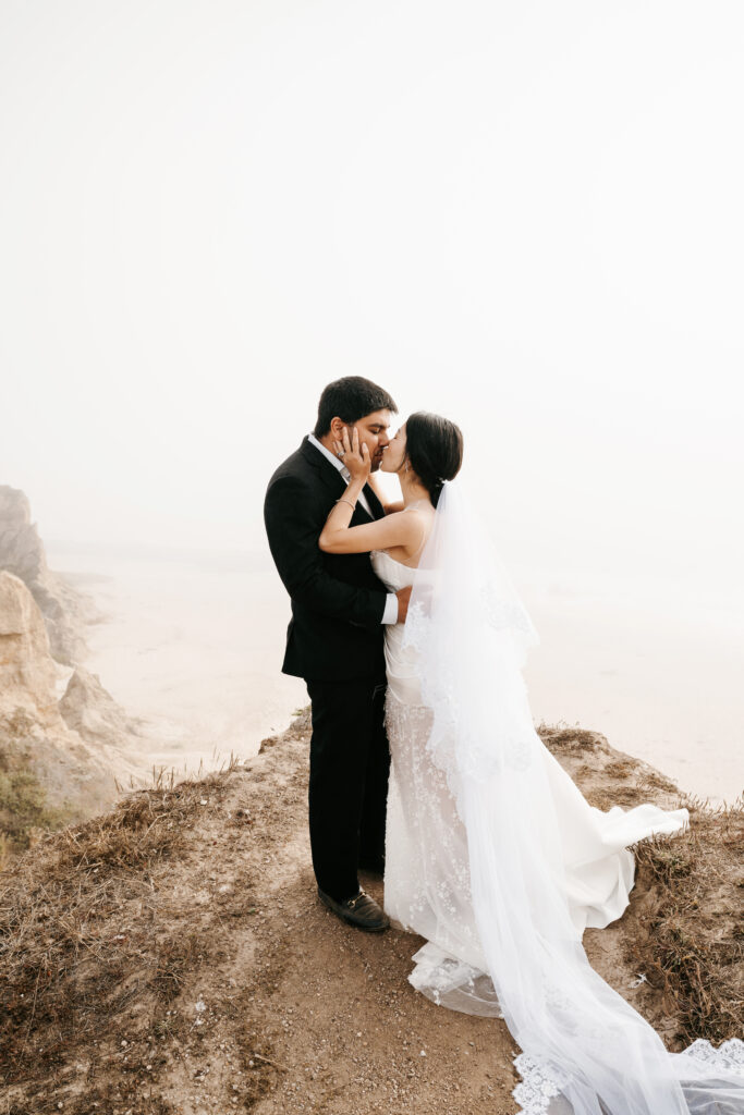 Bride and groom eloping at Half Moon Bay on the cliff side by the ocean