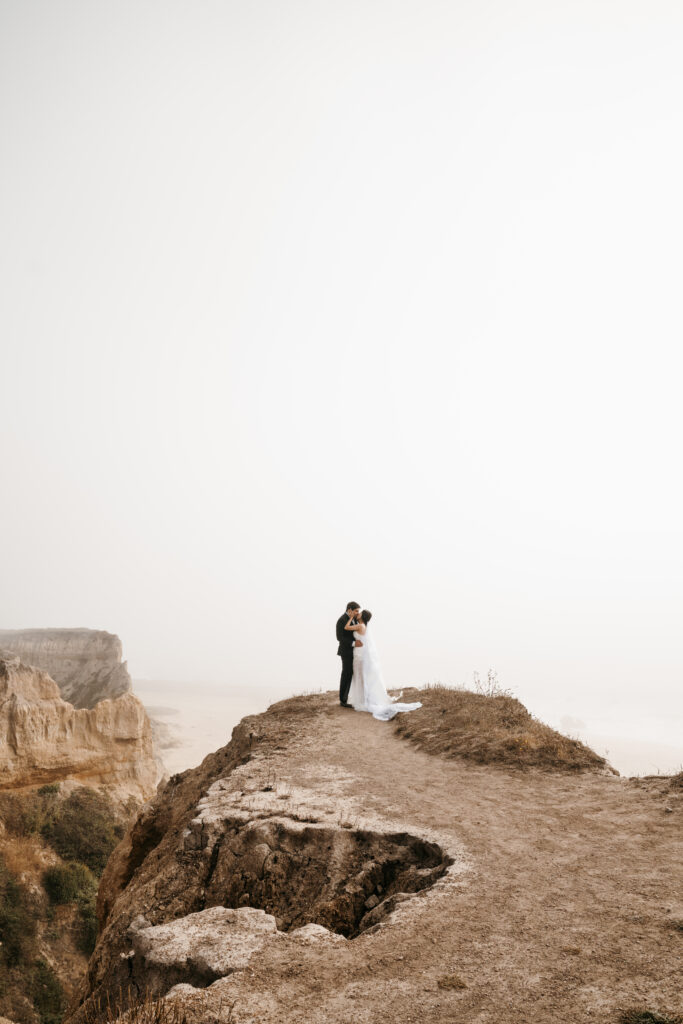 Bride and groom eloping at Half Moon Bay on the cliff side by the ocean