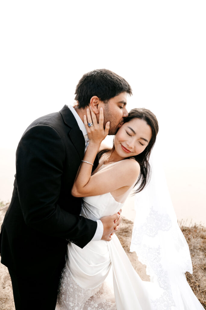 Bride and groom eloping at Half Moon Bay on the cliff side by the ocean