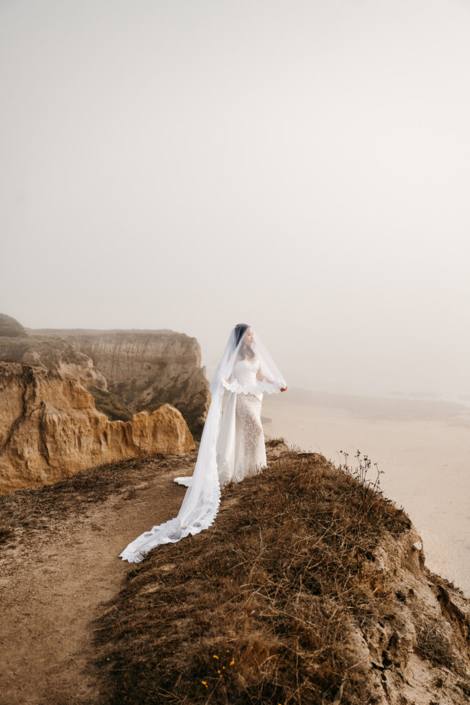 Bride under her veil on the cliff side