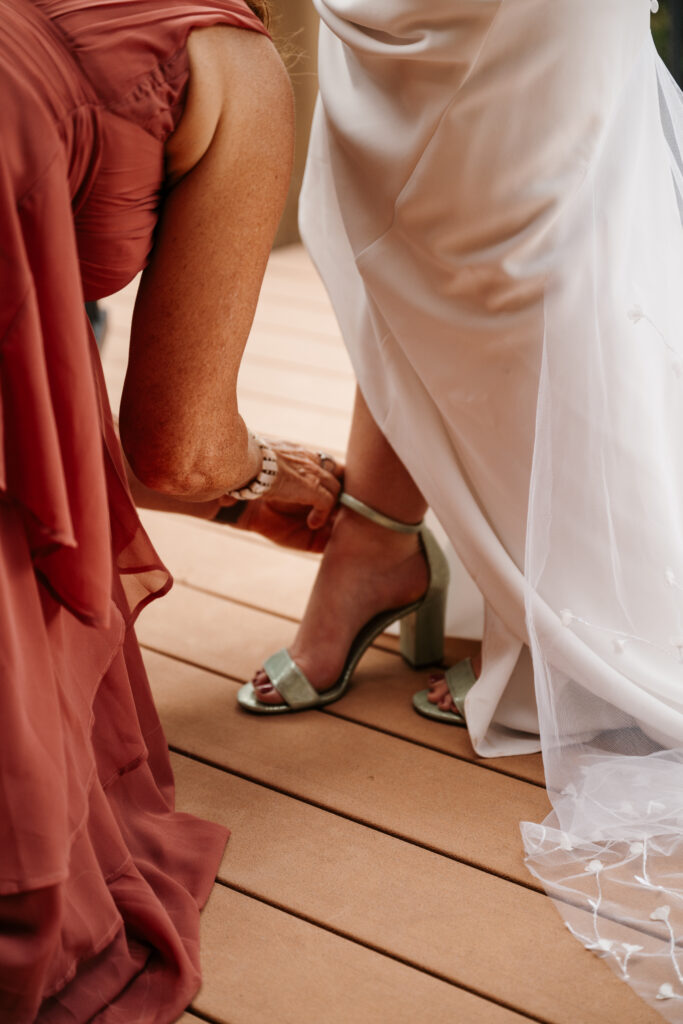 Mom putting shoes on the bride