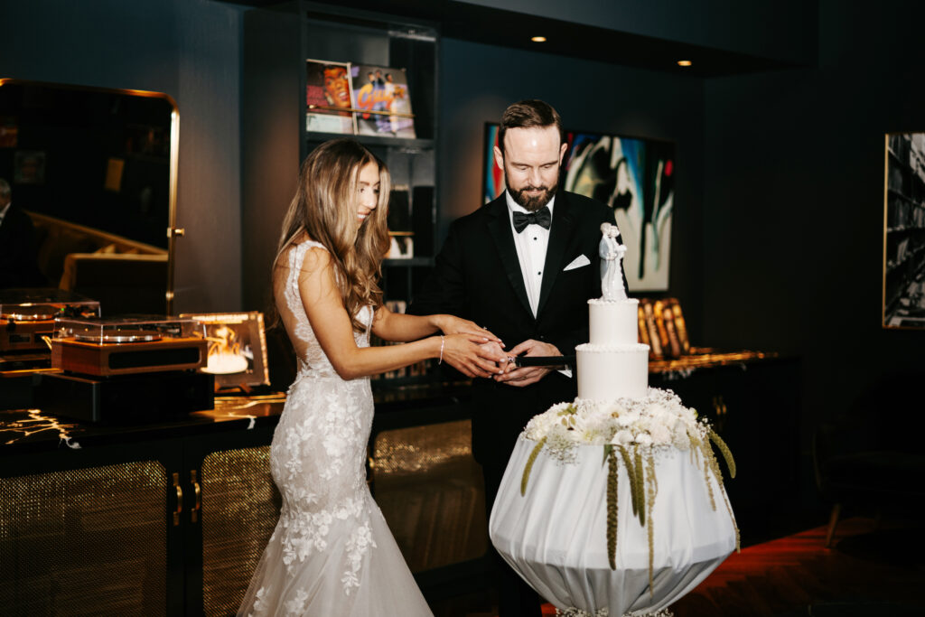Bride and groom cutting cake with vintage cake topper
