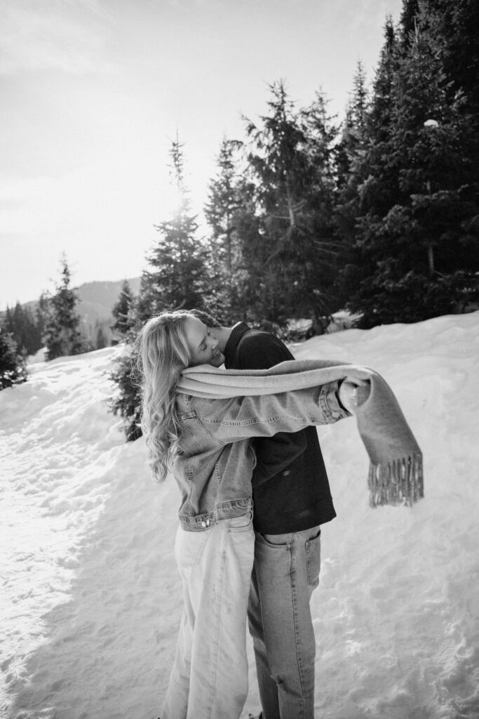 Couple running through the pine trees in the snow