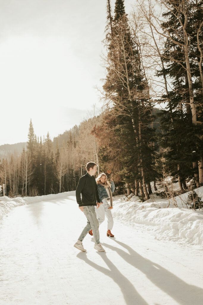 Couple running through the pine trees in the snow