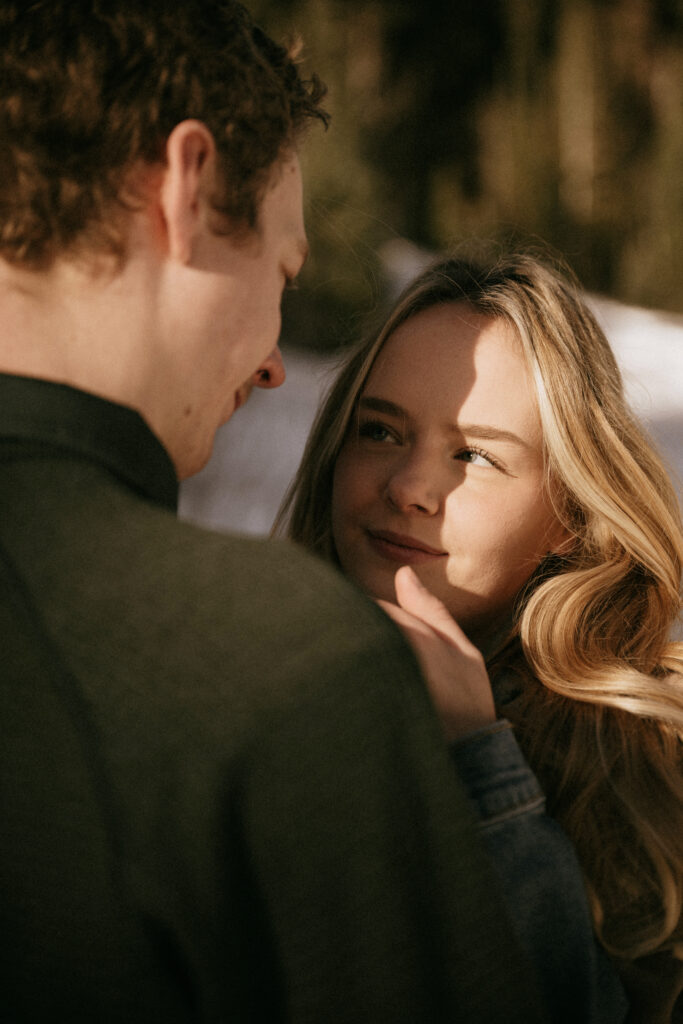 Couple running through the pine trees in the snow