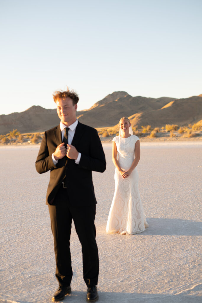 Groom adjusting jacket during Bonneville Salt Flats wedding portraits at sunset